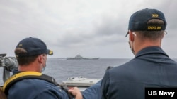 資料照片：美國海軍公佈的照片顯示，兩位美國海軍中校羅伯特·J·布里格斯與理查德·D·斯萊2021年4月4日在阿利·伯克級導彈驅逐艦“馬斯廷號”駕駛艙進行水面接觸觀察。照片中可見中國"遼寧號"航空母艦及其舷號。