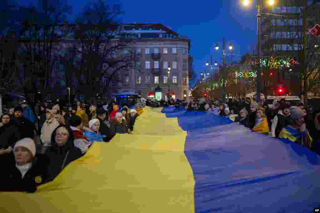 Вильнюс, Литва Демонстранты несут гигантский украинский флаг в преддверии третьей годовщины полномасштабного вторжения России в Украину, 23 февраля 2025 года
