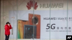 在北京一位女士站在華為手機的廣告看板前(2020年3月8日)