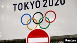 东京街头交通警示牌后的东京奥运会的标识。（2020年3月23日）