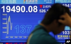 一位香港市民行經股市指數報告版前