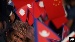 尼泊爾政府官員手持尼泊爾和中國國旗，在公路旁迎接中國國家主席習近平的到來。（2019年10月12日）