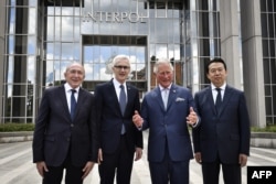 2018年5月8日，国际刑警组织主席孟宏伟（右）和秘书长斯托克，法国内政部长和英国威尔士亲王查尔斯王子在法国里昂的国际刑警组织总部门前合影。