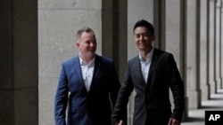 香港移民官梁镇罡和他的英籍同性婚姻伴侣史葛携手走在香港终审法院外。(2019年6月6日)