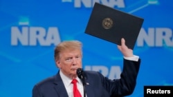 特朗普總統星期五在美國全國步槍協會講話時手舉停止批准武器貿易條約程序的政令。