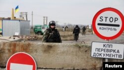 一名烏克蘭軍人站在親俄羅斯的活動分子在克里米亞設立路卡之外 .