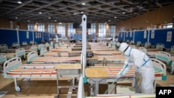 戴口罩的工人正在給一個關閉的武漢方艙醫院消毒。 （2020年3月10日）