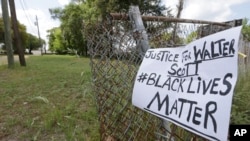 在斯科特被枪杀地点附近的栅栏上挂着一个呼吁执法公正的标语牌（2015年4月8日）