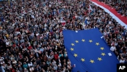 人群在華沙打出歐盟和波蘭旗幟，抗議波蘭保守派政府改造波蘭法院。 （2018年7月3日）