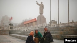 2017年3月23日數名維吾爾族人坐在位於中國新疆維吾爾自治區喀什市中國已故的毛澤東主席雕像附近。