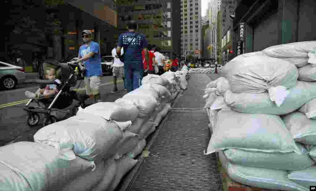 Pedestrians walk past sandbags used to control possible floods at downtown Manhattan in New York, August 26, 2011. New York ordered residents in low-lying areas to evacuate before the onslaught this weekend of massive Hurricane Irene. (Reuters Image)