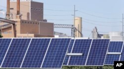 资料照片：内布拉斯加州弗里蒙特的一组太阳能电池板，后面可见一家发电场。(2018年5月31日)
