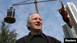 资料照：创作国殇之住的丹麦雕塑家高志活（Jens Galschiot）在香港维多利亚公园内树立的他的雕塑作品“疯牛病”前接受记者采访。（2005年12月15日）