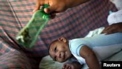 一位媽媽用綠色的瓶子刺激頭小畸形4個月大的兒子(2016年2月11日)