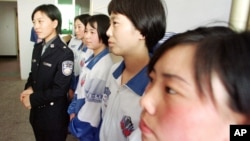 一位女警官站在中國東北一個勞教營的女性囚犯旁(資料照片)