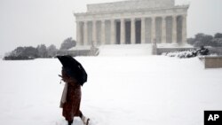 路人於風雪當中在美國首都華盛頓的林肯紀念堂前面經過