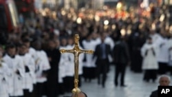 人们在伯利恒圣诞教堂外的圣诞庆祝活动中举着十字架。(2012年12月24日) 