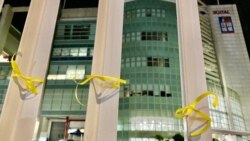 有市民在蘋果日報大樓外的鐵欄上綁上象徵自由的黃絲帶。 (美國之音湯惠芸)