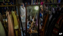 ແວ່ນແຍງສະທ້ອນໃຫ້ເຫັນແມ່ຍິງ ຂະນະທີ່ພວກເຂົາເຈົ້າກຳລັງເບິ່ງເຄື່ອງນຸ່ງ ຢູ່ທີ່ຕະຫຼາດຂາຍເຄືື່ອງນຸ່ງປີໃໝ່ ໃນນະຄອນຫຼວງປັກກິ່ງ ເມື່ອວັນທີ 1 ມັງກອນ, 2024.