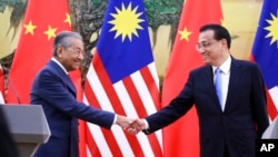 马来西亚总理马哈蒂尔和中国总理李克强在人民大会堂举行记者会后握手。（2018年8月20日） 