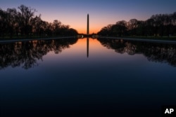 在华盛顿国家大草坪上，黎明之前，华盛顿纪念碑和绿树的影子投射在映影池（2016年4月17日）。