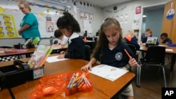 ນາຍ​ຄູ​ສອນ​ປໍ​ນຶ່ງ ທ່ານ​ນາງ ຊາ​ຣອນ ພາ​ສັນ, ເສື້ອ​ຂຽວ, ກວດ​ກາ​ນັກ​ຮຽນ​ທີ່​ກຳ​ລັງ​ຮຽນ​ຢູ່​ໃນ​ຫ້ອງ​ຮຽນ ຢູ່​ໂຮງ​ຮຽນ ວິນ​ເທີ ກາ​ເດັນ ຄ​ຣິ​ສ​ຕຽນ, ລັດ ຟ​ລໍ​ຣິ​ດາ, 29 ສິງ​ຫາ 2024. (AP Photo/John Raoux)