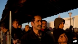 在希腊与马其顿的边界上的一个难民营里，叙利亚难民排队领取食物。（2016年2月25日）