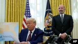 2025年2月13日，在白宮橢圓形辦公室，唐納德·特朗普總統簽署行政命令後發表演說。站在後邊的是被提名的商務部長人員霍華德·盧特尼克。