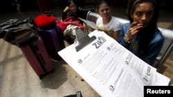  一名哥倫比亞醫療工作者在波哥大公交車總站向乘客散發預防寨卡病毒傳播的信息。 （2016年1月31日）