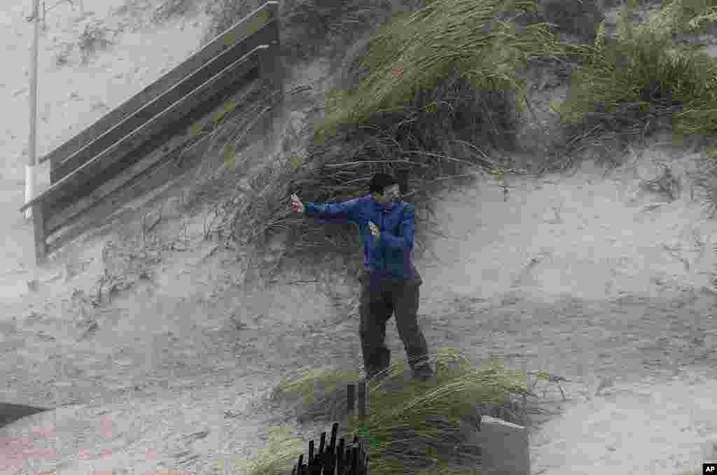 A man struggles against the wind while trying to walk over the dunes as the effects of Hurricane Irene are felt in Nags Head, North Carolin, August 27, 2011. (AP Image)