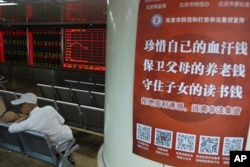 北京一名投資者坐在一個股票交易所內樹立的一張海報旁。海報上寫道：“珍惜自己的血汗錢，保衛父母的養老錢，守住子女的讀書錢“。(2019年6月12日)