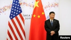 中國國家主席習近平在日本出席G20峰會期間在美中國旗前等候美國總統特朗普前去參加雙邊會談。 （2019年6月29日）