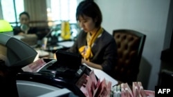 2018年8月8日在上海的一家銀行，員工使用點鈔機點算100元（相當於14.6美元）的鈔票。