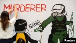 一名香港反送中抗议者在手绘一幅全副武装的蒙面港警开枪实弹射击一名抗议学生情景的壁画。（2019年10月2日）