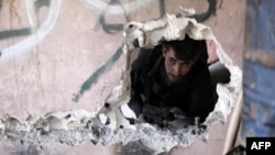  2016年2月26日，一名敘利亞反政府戰鬥人員在大馬士革郊外烏塔地區的阿濱鎮一處地點進行觀察。 