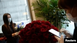 北京金融中心一家花店的工作人员带着口罩为情人节的花束订购做准备。（2020年2月14日路透社资料照）