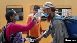 印度一名卫生工作者在孟买一个列车站为旅客量体温（路透社2021年4月7日）