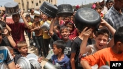 资料照片：被驱离的巴勒斯坦儿童在加沙拉法城排队领取食物。（2024年5月19日）