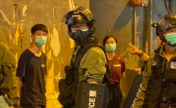 两名高举抗议警方标语的年轻人被警员截查 (美国之音/汤惠芸)