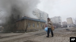 一名婦人走過烏克蘭城市馬里烏伯爾的居民區遭火箭彈襲擊的建築。