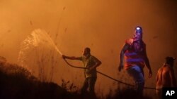 10月16日葡萄牙兩名消防員正用水喉試圖滅野火。