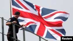 英國皇家海軍海神之子兩栖登陸艦2018年8月3日抵達日本東京一個港口時一名英國水手站在英國國旗前