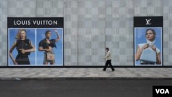 在中國湖北省武漢市，一名男子帶著口罩走過法國奢飾品牌路易威登（Louis Vuitton）的一家門店。 （2020年2月25日）