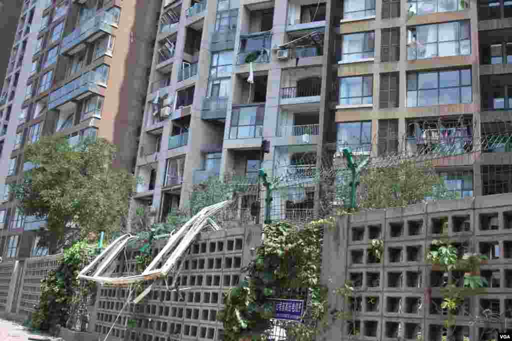 天津爆炸事故现场，核心爆炸区周围多座居民楼窗户被震碎，高速公路桥梁受损，多辆大货车被炸翻，小汽车起火或被砸，多名当地居民仍逗留在事故现场。（美国之音记者东方拍摄）