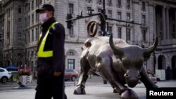 一名戴著口罩的保安走過上海外灘金融牛旁。