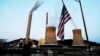 FILE - A U.S. flag flies on tugboat as it passes the coal-fired Mitchell Power Plant on the Ohio River, in Moundsville, West Virginia, Sept. 10, 2017.