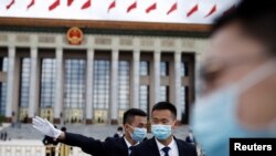 预防病毒传播和减少感染新冠病例，戴口罩可能比保持社交距离或者禁足在家都更为重要。中国保安在正在举行中国人大会议的北京人大会堂外站岗。（路透社2020年5月25日资料照）