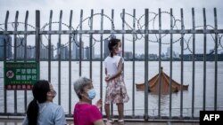 中國武漢居民注視著將要淹沒長江岸邊亭子頂部的洪水。 （2020年7月12日）