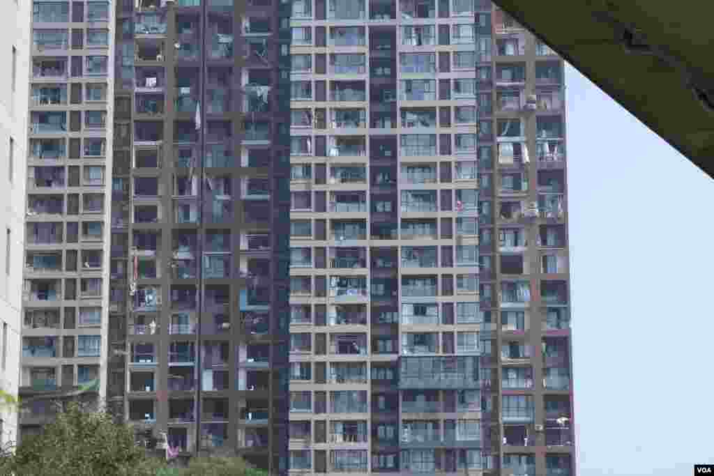 天津爆炸事故现场，核心爆炸区周围多座居民楼窗户被震碎，高速公路桥梁受损，多辆大货车被炸翻，小汽车起火或被砸，多名当地居民仍逗留在事故现场。（美国之音记者东方拍摄）