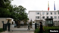 2022年8月8日，一名男子走過緬甸駐北京大使館外站崗的武警士兵。 （路透社照片）